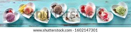 Rustic panorama banner of different ice cream flavors in scoops on individual heart shaped dishes with fresh ingredients on blue wood