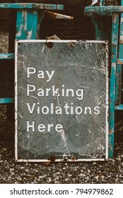 Rustic Pay Parking Violations Here Sign on a Gravel Road at an Old Antique Shop
