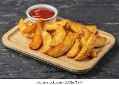 Rustic potatoes with ketchup on light wooden plate on dark wooden background. - Powered by Shutterstock