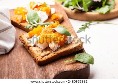 Rustic pumpkin and cheese toast on whole grain bread adorned with fresh greens.