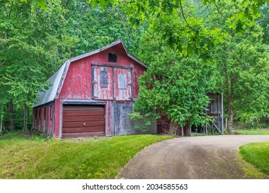 Rustic Red Barn In Lush Forest Setting With Driveway.