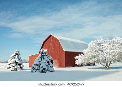 A Rustic Red Barn In Ohio Covered In Fresh Snow With A Bright Blue Sky Background.