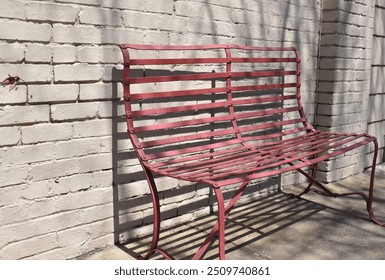 Rustic red bench in sun creating shadows