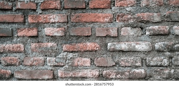 Rustic red brick wall with a weathered appearance.