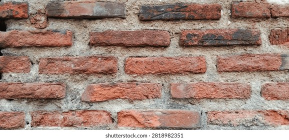 Rustic red brick wall with a weathered appearance.