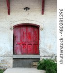 Rustic, red, wooden door is framed by white painted bricks.  Doorway is part of old train station in Stoughton, Wisconsin.