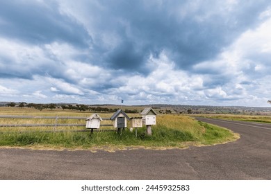Rustic roadside mailboxes in remote area of country New South Wales with Australian flag flying