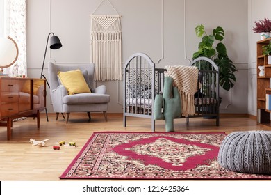 Rustic rug in stylish baby bedroom with grey and vintage furniture, real photo with copy space