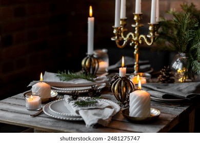 Rustic Scandinavian style zero waste eco-friendly dinner table decor for Christmas or new year family celebration. Wooden table, natural elements like pine cones, fir tree branches, candles