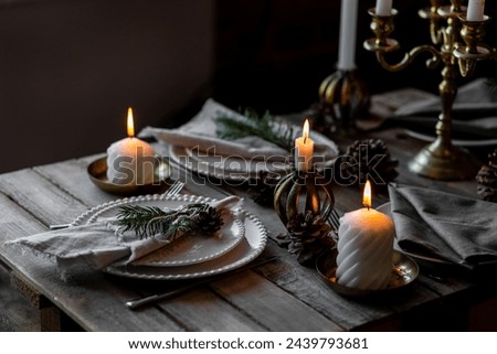 Rustic Scandinavian style zero waste eco-friendly dinner table decor for Christmas or new year family celebration. Wooden table, natural elements like pine cones, fir tree branches, candles