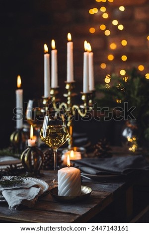 Rustic Scandinavian style zero waste eco-friendly dinner table decor for Christmas or new year family celebration. Wooden table, natural elements like pine cones, fir tree branches, candles