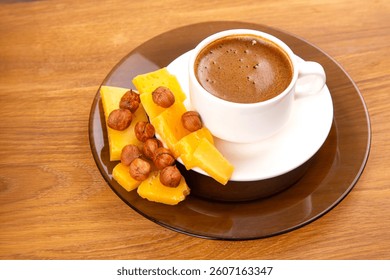 A rustic scene featuring a white cup of bold espresso with a frothy layer, paired with golden cheese slices, displayed on a warm wooden table.