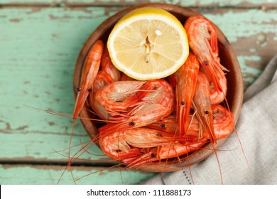 Rustic Serving Of Cooked Shrimp In A Pottery Bowl With Lemon On A Grungy Painted Wooden Table Top