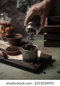 A rustic setup featuring whole coffee beans and ground coffee placed on a wooden board, accompanied by a jar of biscuits in the background. Perfect for conveying warmth and coziness.