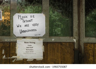 Rustic sign in restaurant window during time of Covid stating restaurant is understaffed and is hiring in a struggling economy, showing the plight of small businesses in the post-pandemic economy. - Shutterstock ID 1983755087