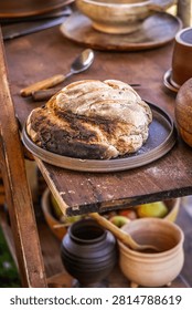 Rustic sourdough bread rests on a wooden shelf with ancient pottery and fresh fruit