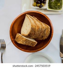 Rustic sourdough bread in a wooden bowl on a restaurant table - Powered by Shutterstock