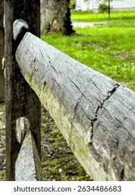 A rustic split-rail fence, crafted from weathered logs, delineates a natural boundary, embodying a charming, traditional aesthetic with its robust wooden posts and rails.