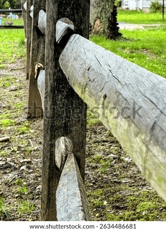A rustic split-rail fence, crafted from weathered logs, delineates a natural boundary, embodying a charming, traditional aesthetic with its robust wooden posts and rails.
