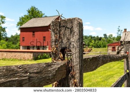 A rustic split-rail fence in sharp focus with the historic bank barn at the Daniel Boone Homestead softly blurred in the background in Birdsboro, Pennsylvania.