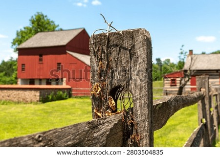 A rustic split-rail fence in sharp focus with the historic bank barn at the Daniel Boone Homestead softly blurred in the background in Birdsboro, Pennsylvania.