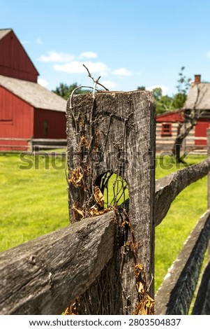 A rustic split-rail fence in sharp focus with the historic bank barn at the Daniel Boone Homestead softly blurred in the background in Birdsboro, Pennsylvania.