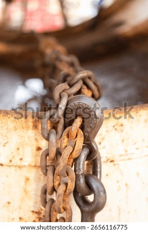 Rustic steel chain with hook is using to fastening and restraining on the heavy object, secure for the transportation. Transporation industrial equipment object, close-up with selective focus.