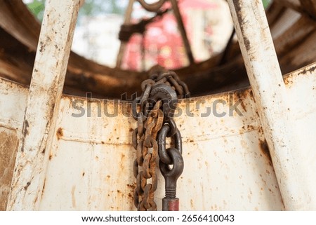 Rustic steel chain with hook is using to fastening and restraining on the heavy object, secure for the transportation. Transporation industrial equipment object, close-up with selective focus.