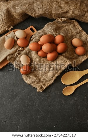 A rustic still life featuring a collection of natural, uncolored eggs scattered on textured burlap fabric, hinting at wholesome ingredients and natural farming practices