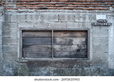 Rustic stone brick wall texture with a boarded-up wooden window, showing decay and industrial architectural detail