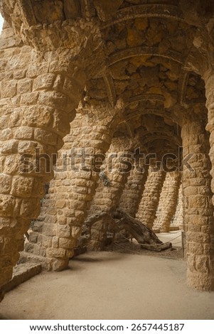 Rustic stone columns and leaning arches in Park Guell, Barcelona, showcasing Antoni Gaudi s unique architecture. Ideal for travel content, architectural features, and European tourism promos.
