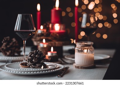 Rustic table decor for Christmas or New Year family dinner. Centrepiece with red candle, dry orange, cone, cinnamon, anise. Zero waste eco-friendly home. Cozy atmosphere, dark background. Close up - Powered by Shutterstock