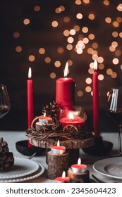 Rustic table decor for Christmas or New Year family dinner. Centrepiece with red candle, dry orange, cone, cinnamon, anise. Zero waste eco-friendly home. Cozy atmosphere, dark background. Close up
