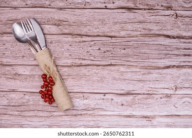 Rustic table setting with cutlery and red currants on wooden background