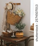 Rustic table styling with daisies and olive tree on a dark wooden table against a white wall. Cottage style home room decoration with summer wild flowers 
