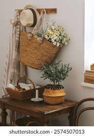 Rustic table styling with daisies and olive tree on a dark wooden table against a white wall. Cottage style home room decoration with summer wild flowers 

