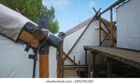 Rustic tents in an african adventure camp nestled in nature, highlighted by their wooden supports and the blue sky above, ideal for an outdoor eco-tourism experience. - Powered by Shutterstock