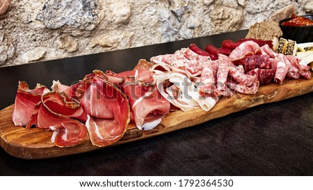 Rustic Tuscan tray with typical products: prosciutto (ham), brawn, finocchiona, crostini, salami, tuscan chilli and sliced pecorino ​​cheese. San Gimignano, Siena, Italy 