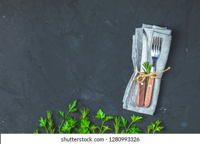 Rustic vintage set of cutlery knife, fork. Black stone concrete surface background, fresh herb decor. Top view, copy space. - Powered by Shutterstock