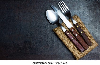 Rustic vintage set of cutlery knife, spoon, fork. Black background. Top view - Powered by Shutterstock