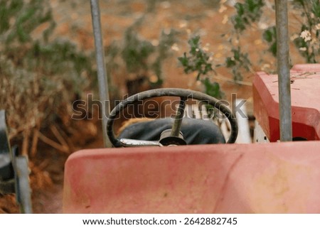 Rustic vintage tractor interior showcasing the steering wheel and worn seat in an autumn landscape, evoking nostalgia for agricultural life