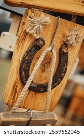 A rustic wall decoration featuring an iron horseshoe mounted on a wooden plaque, complemented by rope details and knots, symbolizing luck and craftsmanship. Perfect for farmhouse-style interiors