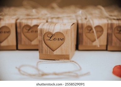 Rustic wedding favor boxes crafted from wood with “Love” engraved in a heart design, tied with twine, creating a charming and eco-friendly aesthetic for wedding guests. - Powered by Shutterstock