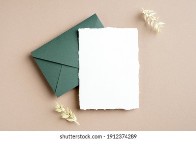 Rustic wedding invitation card mockup, green envelope and dried flowers on pastel beige background. Flat lay, top view, copy space. - Shutterstock ID 1912374289
