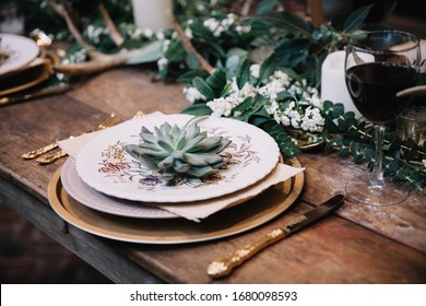 Rustic wedding table seting with vintage plates, green and white eucalyptus garland, gold utensils. Boho style. Table set for an event, party, date or wedding. - Powered by Shutterstock