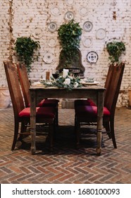 Rustic Wedding Table With Vintage Plates, Green And White Eucalyptus Garland, Deer Antlers, Gold Utensils. Boho Style. Table Set For A Private Dinner, Event, Party, Date Or Wedding. Red Wine Served