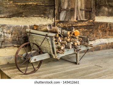 Rustic Wheel Barrow Carrying Fire Wood On A Log Cabin Porch