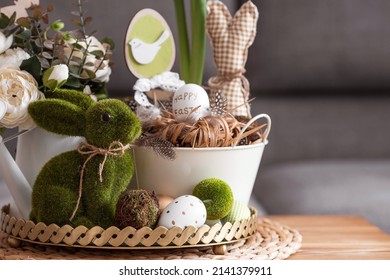 Rustic. White-green colors. Iron planters with Easter eggs, flowers, candles and rabbits in the living room interior on the table. The concept of home comfort in the bright holiday of Easter 2022. - Shutterstock ID 2141379911