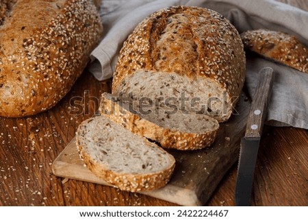 Rustic whole grain bread on a cutting board on a wooden kitchen table