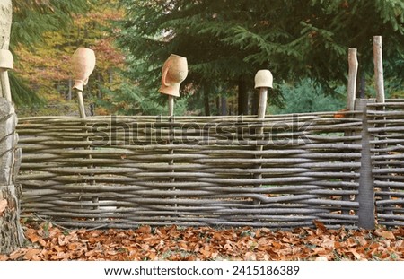 Rustic wicker fence with an old clay pot on it. Brown clay pot on a wicker fence